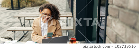 Afro american woman freelancer working remotely while sittiing on cafe terrace 102739510