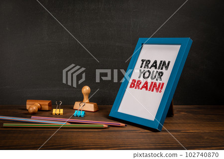 Train Your Brain. Picture frame with text on wooden office table 102740870