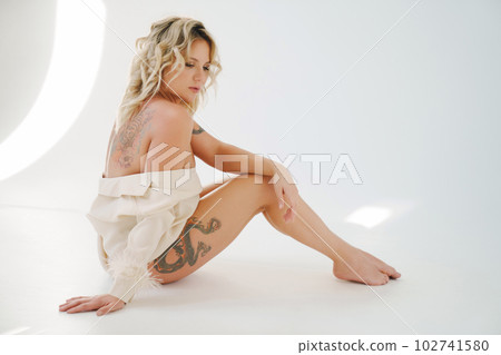 a gentle naked blonde woman in a white shirt on the floor. a gentle naked blonde woman in a white shirt on the floor. 102741580