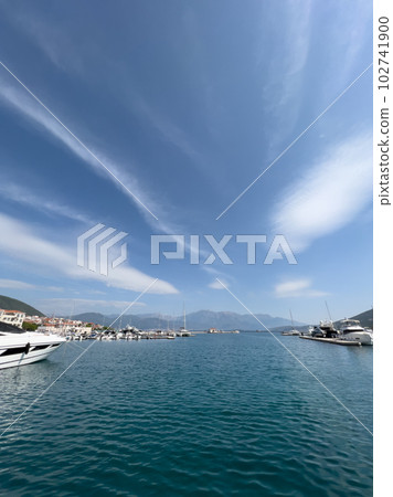 Luxurious marina at the foot of the mountains with expensive yachts against the backdrop of cirrus clouds in the blue sky Luxurious marina at the foot of the mountains with expensive yachts against the backdrop of cirrus clouds in the blue sky 102741900