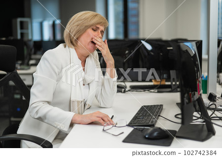 Tired caucasian woman at her desk in the office. Tired caucasian woman at her desk in the office. 102742384