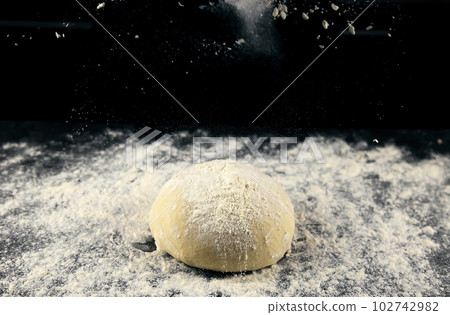 Raw yeast dough sprinkled with flour on a black background. Dough for making bread or pizza. Raw yeast dough sprinkled with flour on a black background. Dough for making bread or pizza. 102742982