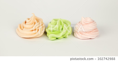 Sweet pastry concept. Three meringues pink green orange on a white background. View from the front. 102742988