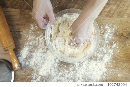 Top view of female hands kneading dough for baking. The concept of making yeast dough. Top view of female hands kneading dough for baking. The concept of making yeast dough. 102742994