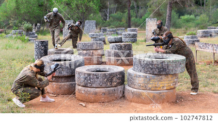 Expressive paintball team running with a marker guns at open playing field Expressive paintball team running with a marker guns at open playing field 102747812