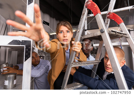 European girl on ladder in quest room with other multiracial people European girl on ladder in quest room with other multiracial people 102747950