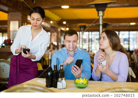 Couple using smartphones to order food in restaurant 102748015