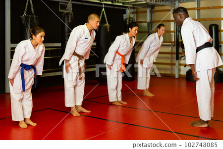 Group of athletes in kimono greet the karate trainer at gym 102748085