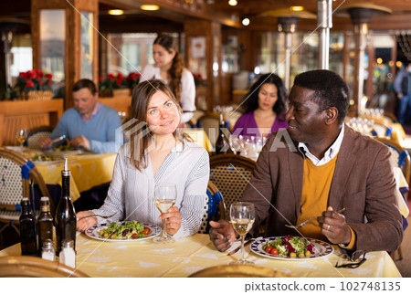 Husband and wife eating and talking in restaurant Husband and wife eating and talking in restaurant 102748135