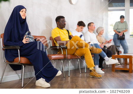 Young Asian girl sitting in lobby of job center Young Asian girl sitting in lobby of job center 102748209