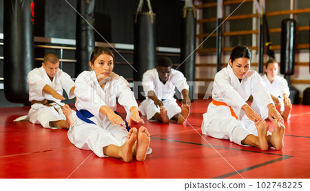 Group of people in kimono stretching before karate training 102748225
