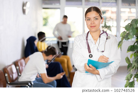 Portrait of young female doctor wearing uniform with folder 102748526