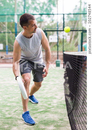 Doubles play in an outdoor paddle game court Doubles play in an outdoor paddle game court 102748544