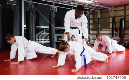 Man and women in kimono doing push-ups with trainer 102748606