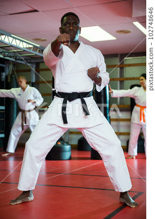 African american man in kimono fighting stance at karate training closeup African american man in kimono fighting stance at karate training closeup 102748646