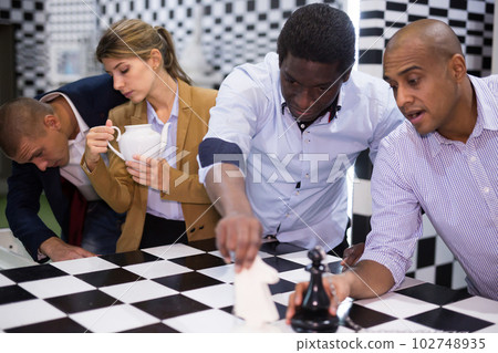 Afro-american man in quest room with colleagues, trying to find solution of conundrum 102748935