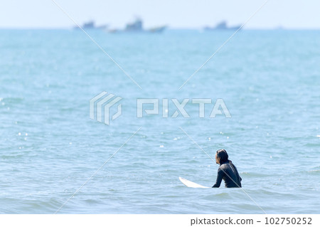 A man on a surfboard waiting for a wave 102750252
