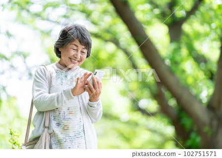 A senior woman who operates a smartphone, an old woman who touches a smartphone outdoors A senior woman who operates a smartphone, an old woman who touches a smartphone outdoors 102751571