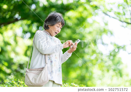 A senior woman who operates a smartphone, an old woman who touches a smartphone outdoors 102751572