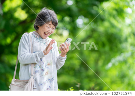A senior woman who operates a smartphone, an old woman who touches a smartphone outdoors 102751574