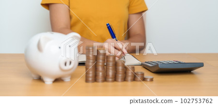 Money Saving for Future Plan, Retirement fund, Pension, Investment, Wealth Business and Financial concepts. Woman Counting and calculate money with coins stack with piggy bank for deposit 102753762
