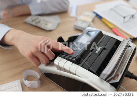 Finger of accountant pushing button to start bill counter Finger of accountant pushing button to start bill counter 102756321
