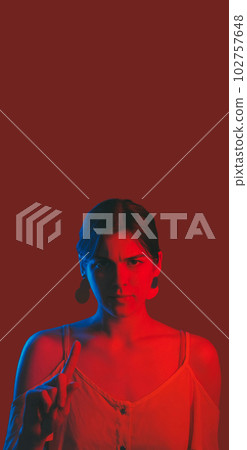 Warning gesture. Danger notice. Serious strict neon color light woman raising finger attention isolated on dark red empty space background. 102757648