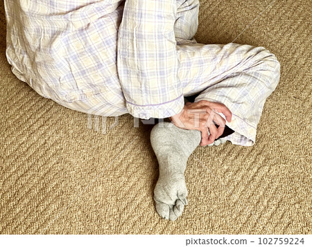 一位穿著睡衣的老婦人的手從後面摩擦她的腳踝 一位穿著睡衣的老婦人的手從後面摩擦她的腳踝 102759224