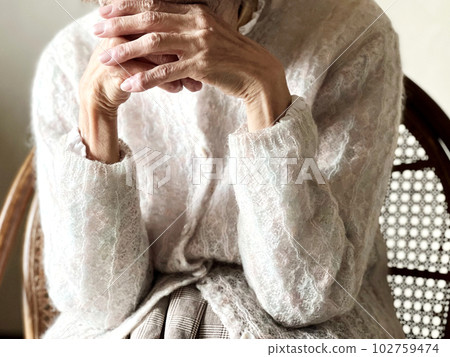 An elderly woman looking down with her fingers crossed on her forehead An elderly woman looking down with her fingers crossed on her forehead 102759474