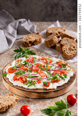 Homemade butter board with tomatoes, red onions and herbs and baguette pieces vertical view Homemade butter board with tomatoes, red onions and herbs and baguette pieces vertical view 102759552