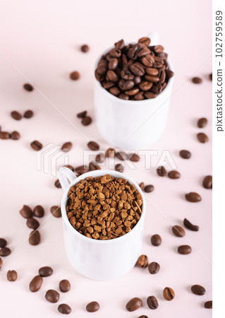 Choice between instant coffee and roasted coffee beans in cups on pink background vertical view Choice between instant coffee and roasted coffee beans in cups on pink background vertical view 102759589