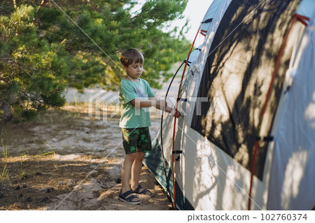 cute little caucasian boy helping to put up a tent. Family camping concept cute little caucasian boy helping to put up a tent. Family camping concept 102760374