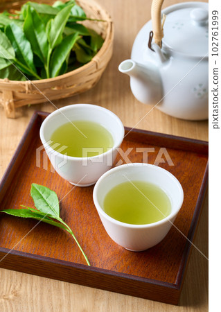 Tea brewed in a teapot and raw tea leaves Tea brewed in a teapot and raw tea leaves 102761999