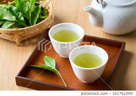 Tea brewed in a teapot and raw tea leaves 102762000
