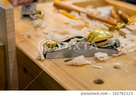 Modern carpenter plane with wooden shavings at workshop 102762123