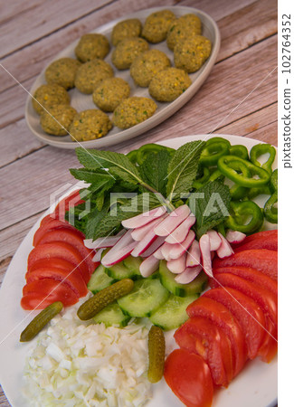 Plate of fresh vegetable salad, tomato, cucumber, onion, gherkin, radish, mint leaves and falafel Plate of fresh vegetable salad, tomato, cucumber, onion, gherkin, radish, mint leaves and falafel 102764352