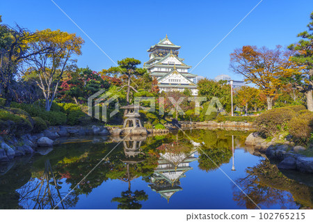 The Osaka Castle tower reflected in the pond in the Japanese garden, the season of autumn leaves 102765215