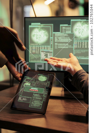 Modern hackers trying to crack firewall encryption on tablet, working at night with computers to steal data. Planting malware and hacking network server online, phishing concept. 102765844