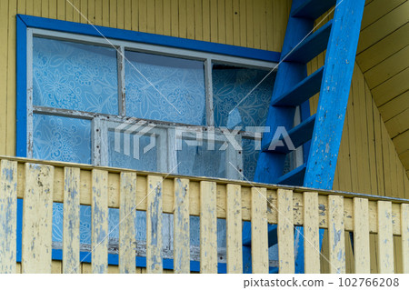 Old yellow wooden balcony - blue wooden windows 102766208