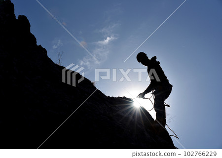 Silhouette of a rock climber hanging on the wall 102766229