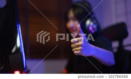 Female cyber hacker gamer in headphone showing thumb up after hacking programming system success Female cyber hacker gamer in headphone showing thumb up after hacking programming system success 102766488