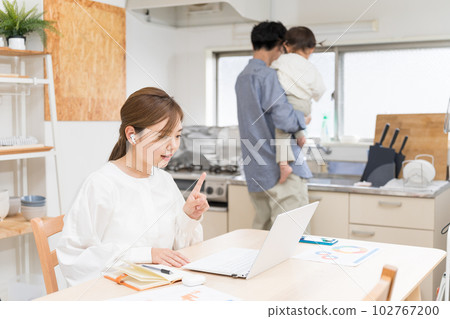 A married woman working remotely in the dining room while her dad takes care of her 102767200
