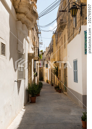 Narrow medieval street with stone houses in Mdina, Malta 102769507