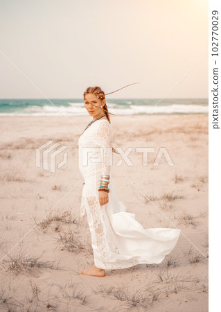 woman sea white dress. Model in boho style in a white long dress and silver jewelry on the beach. Her hair is braided, and there are many bracelets on her arms. woman sea white dress. Model in boho style in a white long dress and silver jewelry on the beach. Her hair is braided, and there are many bracelets on her arms. 102770029