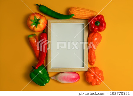 Blank wooden picture frame with vegetables on orange background, Healthy food background, vegetarian food concept Blank wooden picture frame with vegetables on orange background, Healthy food background, vegetarian food concept 102770531