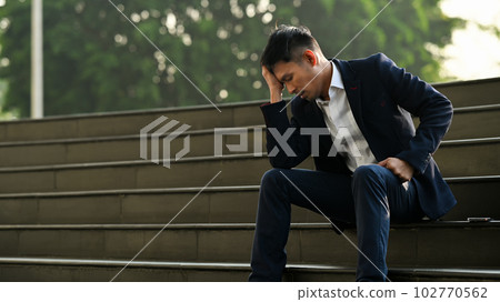 Image of upset man employee sitting on stairs outside office building, financial crisis, unemployed concept Image of upset man employee sitting on stairs outside office building, financial crisis, unemployed concept 102770562