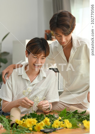 Happy moment loving homosexual couple spending weekend together, enjoying arranging flowers in living room 102770566
