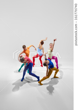 Group of talented, artistic female ballet dancers in bright, multicolored clothes performing against grey studio background Group of talented, artistic female ballet dancers in bright, multicolored clothes performing against grey studio background 102770740