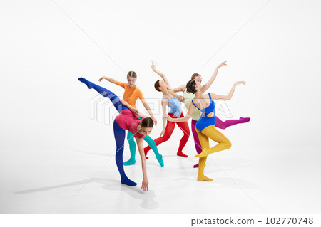 Group of artistic female ballet dancers in bright, multicolored clothes performing, dancing against grey studio background 102770748