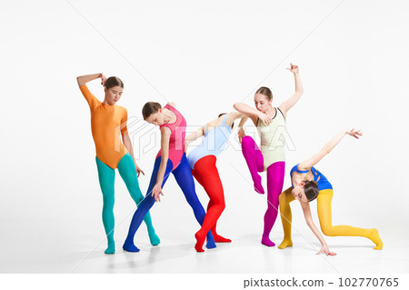 Expressive dance. Artistic young girls, ballet dancers in bright clothes making performance against grey studio background Expressive dance. Artistic young girls, ballet dancers in bright clothes making performance against grey studio background 102770765